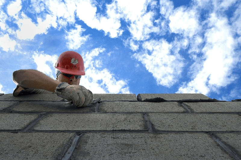 pracownik budowlany murujący ściany, murarz, murowanie z bloczka betonowego, Roboty murarskie i tynkarskie