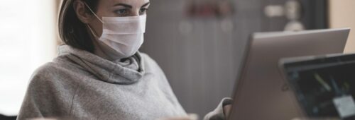 kobieta pracująca zdalnie przed komputerem w masce przeciwbakteryjnej, homeoffice