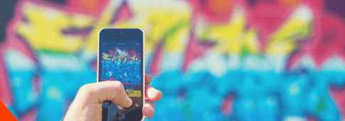 człowiek robiący zdjęcie iphone'm ścianie z kolorowym grafitti.