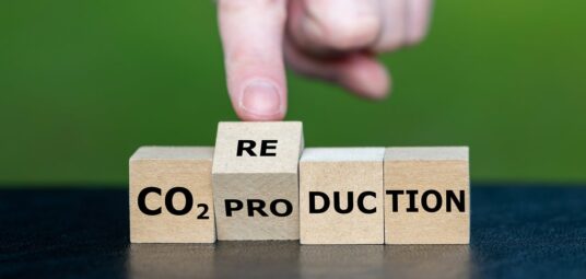 produkcja CO2, ślad węglowy, klocki drewniane z napisem CO2 Production, palec obracający drewniane klocki