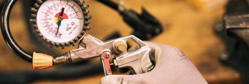 mechanik naprawiajacy rower, miernik ciśnienia w oponach, reduktor do gazu