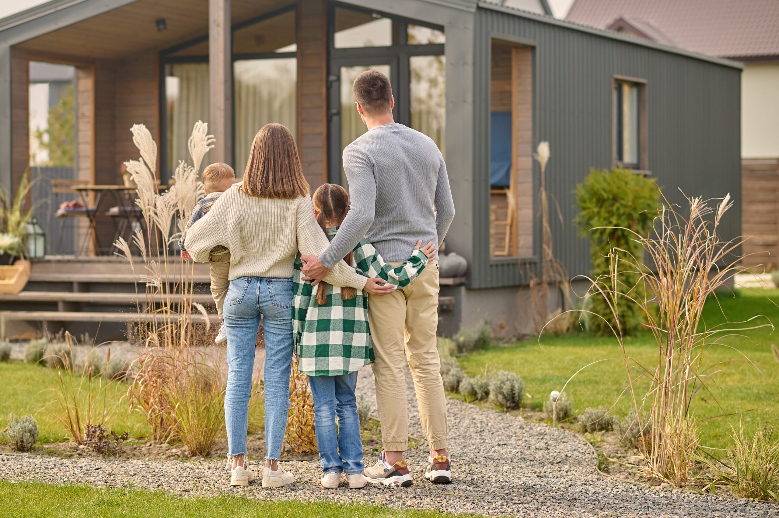 szczęśliwa rodzina przytula się na tle swojego wymarzonego domu ze smart home